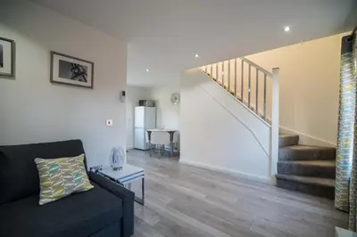 a living room with a black couch and stairs at Alma Villa in Falkirk