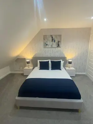 a bedroom with a large bed with blue pillows at Alma Villa in Falkirk