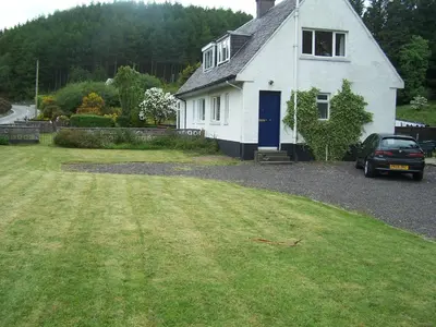 a white house with a car parked in front of it at Feochan View in Oban