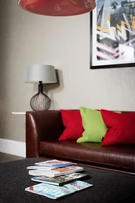 a living room with a brown couch with colorful pillows at Malmaison Glasgow in Glasgow