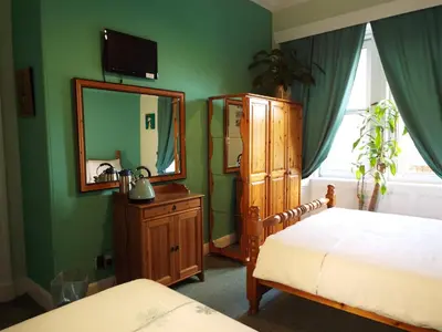 a bedroom with a bed and a dresser and a mirror at Badjao B&B in Edinburgh