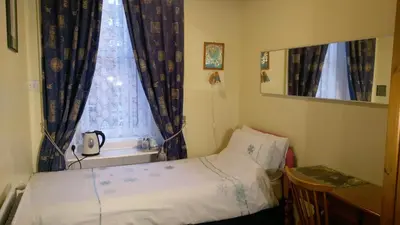a small bedroom with a bed and a window at Badjao B&B in Edinburgh