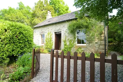 a house with a fence and a dog on top of it at Springburn Cottage in Strachur