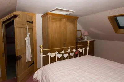 a bedroom with a bed and a wooden cabinet at Springburn Cottage in Strachur