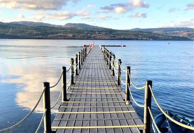 a dock on a body of water with a boat at Springburn Cottage in Strachur