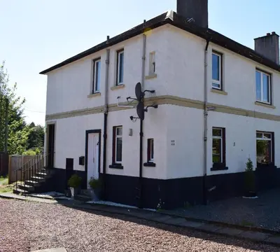 an old white house with a door on a street at Kelpies Serviced Apartments - McClean in Falkirk