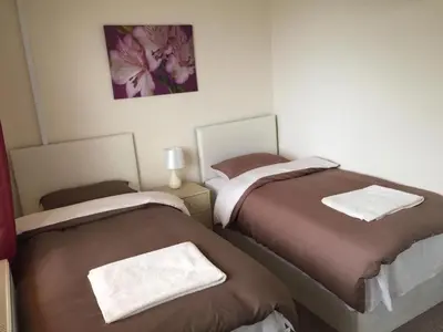 a bedroom with two beds with towels on them at Laughing Buddha Guesthouse in Uddingston