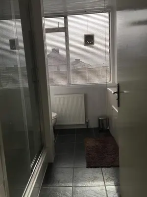 a bathroom with a toilet and a glass door at Laughing Buddha Guesthouse in Uddingston