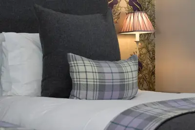 a bedroom with a bed with a pillow and a lamp at Glenegedale House in Kintra