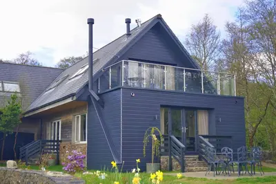 a blue house with a balcony on top of it at Melfort Pier & Harbour Resort in Kilmelford