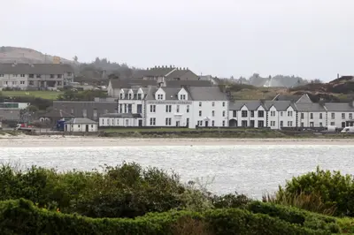 a large white house sitting next to a body of water at No. 1 Charlotte Street in Port Ellen