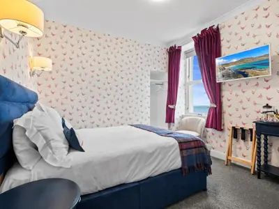 a bedroom with a bed and a table and a window at No. 1 Charlotte Street in Port Ellen