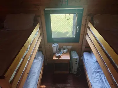 two beds in a room with a table and a window at MacDonald Cabins in Kinlochleven