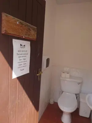 a bathroom with a toilet and a sign on the door at MacDonald Cabins in Kinlochleven
