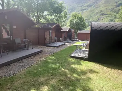 a cabin with chairs and a table in the yard at MacDonald Cabins in Kinlochleven