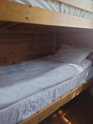 a wooden bunk bed with white sheets on it at MacDonald Cabins in Kinlochleven