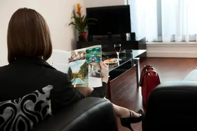 a woman sitting in a chair reading a magazine at The Spires Serviced Apartments Glasgow in Glasgow