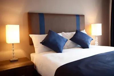 a bedroom with a bed with blue pillows and two lamps at The Spires Serviced Apartments Glasgow in Glasgow