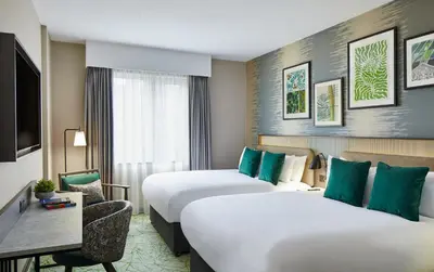 a hotel room with two beds and a tv at Leonardo Royal Hotel Glasgow in Glasgow