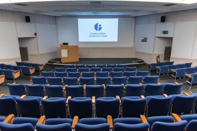 a lecture hall with blue chairs and a screen at The Golden Jubilee Hotel in Clydebank