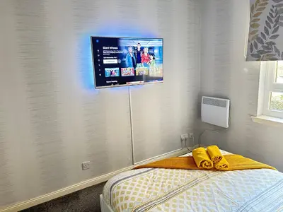 a bedroom with a tv on the wall at Paisley Central Apartment #3 in Paisley