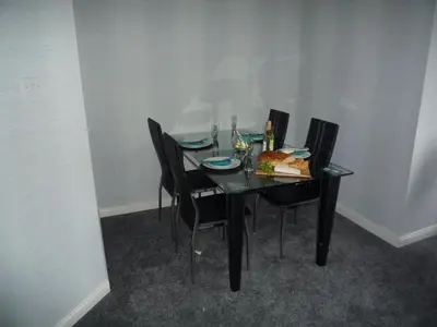 a black table with chairs and a plate of food on it at Paisley Central Apartment #3 in Paisley