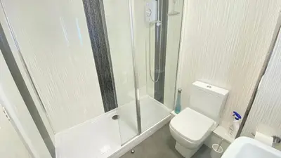 a bathroom with a shower and a toilet and a sink at Paisley Central Apartment #3 in Paisley