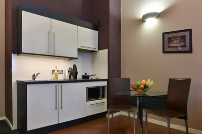 a kitchen with white cabinets and a table with chairs at Fraser Suites Glasgow in Glasgow