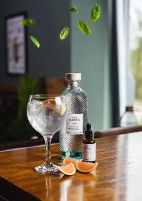 a bottle of alcohol and a glass of water and orange slices at Ben Cruachan Inn - Restaurant, Pub with Rooms in Loch Awe