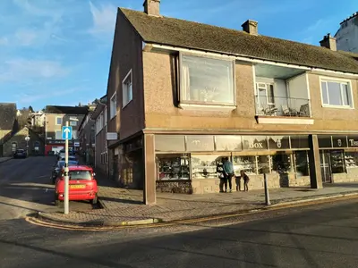 a red car parked in front of a store on a street at bayviewapartment in Oban