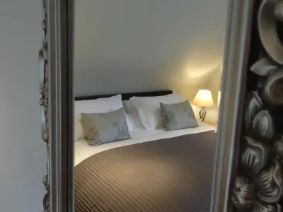 a mirror reflecting a bed with pillows on it at Coach House at The Glen in Helensburgh