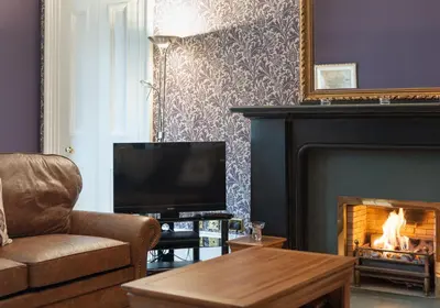 a living room with a fireplace and a television at The Coates Gardens Residence in Edinburgh