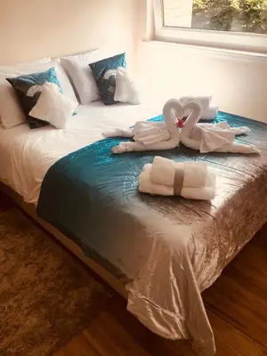 two swans are sitting on top of a bed at King Court Apartment in Motherwell