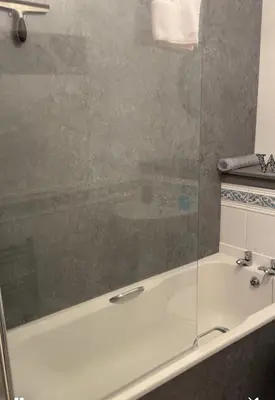 a bathroom with a tub and a glass shower at King Court Apartment in Motherwell