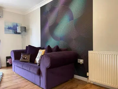 a purple couch in a living room with a wall at King Court Apartment in Motherwell