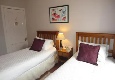 a bedroom with two beds and a table with a lamp at Sebright Holiday Apartment in Dunoon