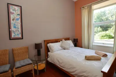 a bedroom with a bed and a window and a chair at Sebright Holiday Apartment in Dunoon