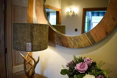 a lamp with a vase of flowers next to a mirror at Benoch Lomond Castle in Alexandria
