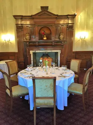 a dining room with a table and a fireplace at Garvock House Hotel in Dunfermline