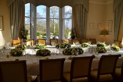 a dining room with a table with flowers on it at Garvock House Hotel in Dunfermline