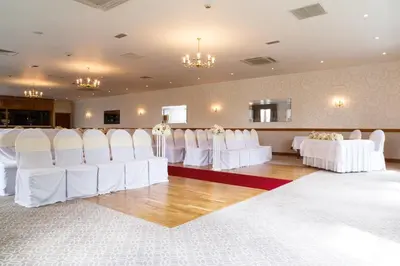 a set up for a wedding in a room with white chairs at Garvock House Hotel in Dunfermline
