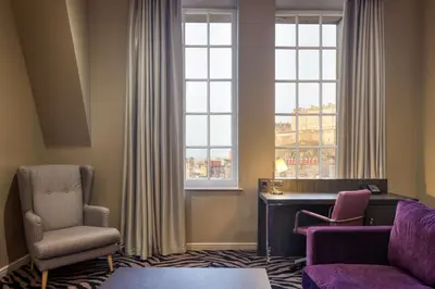 a living room with two chairs and a desk and two windows at Doubletree by Hilton Edinburgh City Centre in Edinburgh