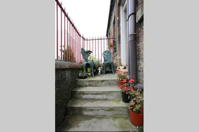 a stairway with chairs and flowers on a house at Almada Apartment in Hamilton