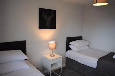 a bedroom with two beds and a lamp on a table at 3 Bedroom-Kelpies Serviced Apartments Bruce in Falkirk