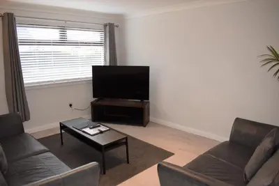 a living room with a couch and a flat screen tv at 3 Bedroom-Kelpies Serviced Apartments Bruce in Falkirk