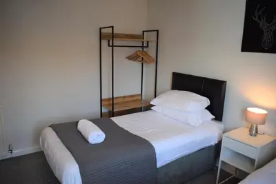 a bedroom with a bed with white sheets and pillows at 3 Bedroom-Kelpies Serviced Apartments Bruce in Falkirk