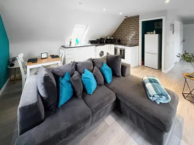 a living room with a brown couch with blue pillows at The Snug in Harthill