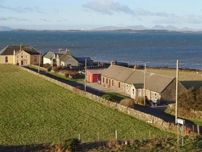 a row of houses on a hill next to the ocean at Charlies Cottage in Muasdale