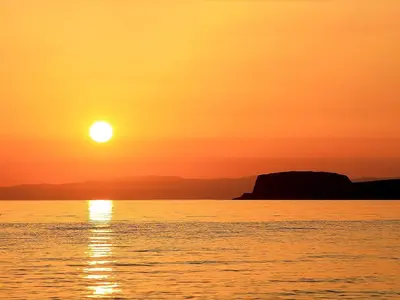a sunset over the water with the sun setting at Charlies Cottage in Muasdale
