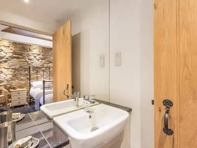 a bathroom with a white sink and a bedroom at The Hayloft in Blitterlees